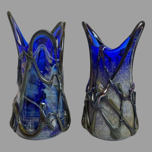 Main photo of signed studio glass vases displayed side by side. The 2 vases although very similar in appearance are nowhere near identical. They look great displayed together or individually with or without flowers. Difficult to describe. Like the splashback of water when a rock is dropped into the sea is what they remind me of.