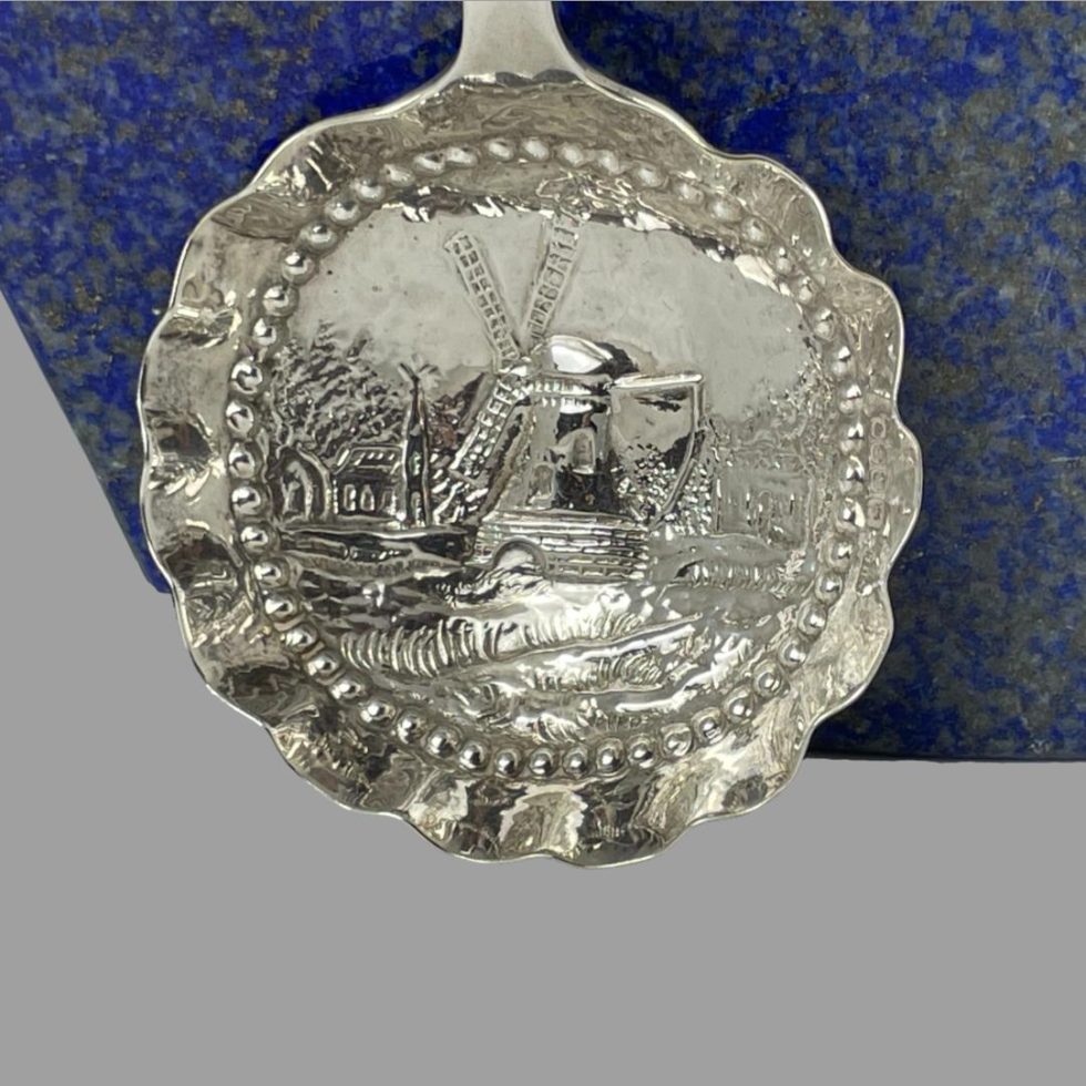 A close up photo of the centre of the Dutch silver ladle spoon bowl showing the Dutch windmill scene.