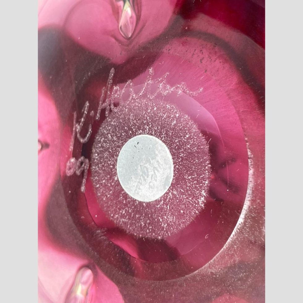 Close up photo of the artists signature and faded original sticker on the base of the pink lotus art glass.