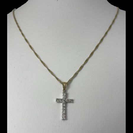 Main photo of gold diamond cross & chain displayed on a stand with the diamond encrusted front of cross forward facing. The yellow gold chain is a flat curb chain which does not look odd with the white gold cross at all perhaps because of the diamonds.