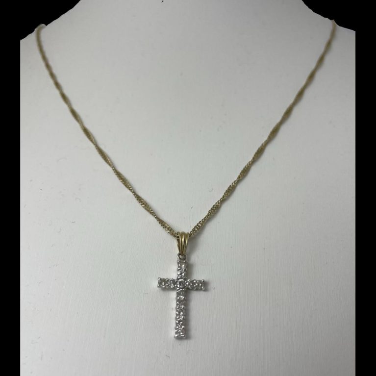 Main photo of gold diamond cross & chain displayed on a stand with the diamond encrusted front of cross forward facing. The yellow gold chain is a flat curb chain which does not look odd with the white gold cross at all perhaps because of the diamonds.