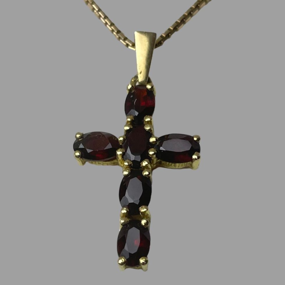 Close up photo of gold garnet cross & chain showing the cross forward facing in close up. The deep red of the garnets and the gold marry beautifully.