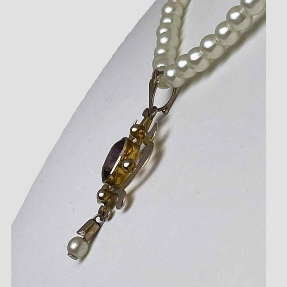 Photo of Edwardian gold pendant collar seen with the pendant in close up and from a side angle to show the depth. The pendant is facing left.