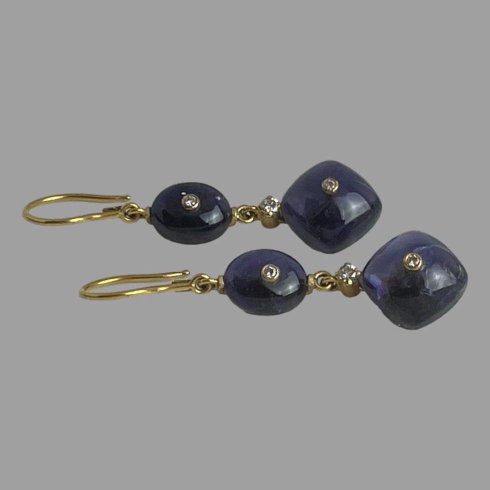 Photo of gold iolite diamond earrings displayed vertically on a flat surface with the hook ends to the left.