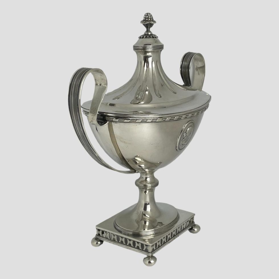 Photo of Swedish silver soup tureen almost at eye level and seen posed diagonally with one side facing right corner and handles to bottom left and top right corner.