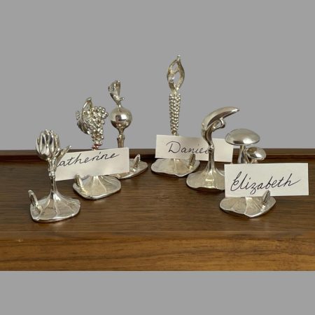 Main photo of Italian name card holders displayed on top of its closed wooden case with shortest in foreground. 3 of the name card holders are holding name cards