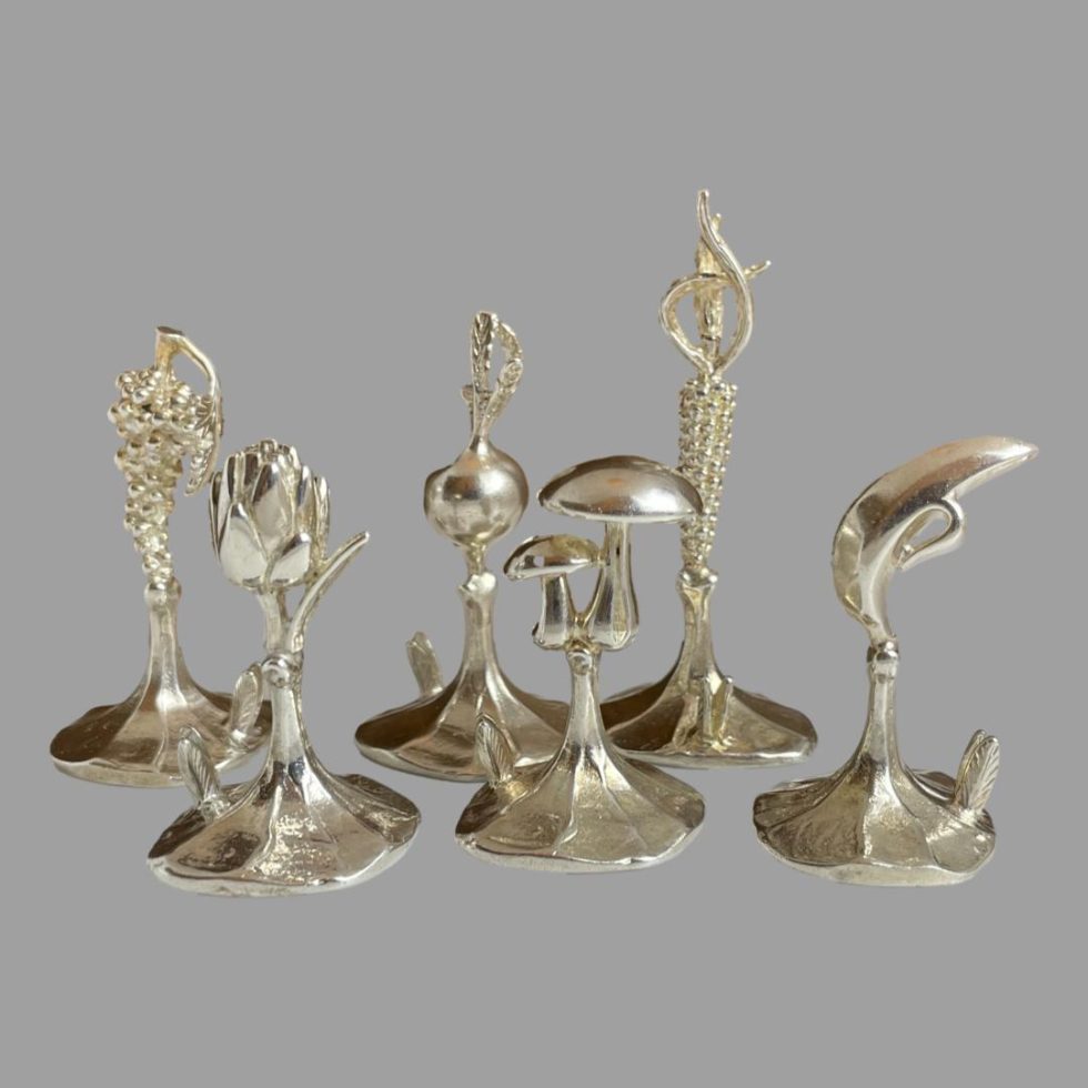 A photo of all 6 Italian name card holders seen in a warmer coloured light and from an eye level. The mushrooms one (my particular favourite) is in the centre foreground.