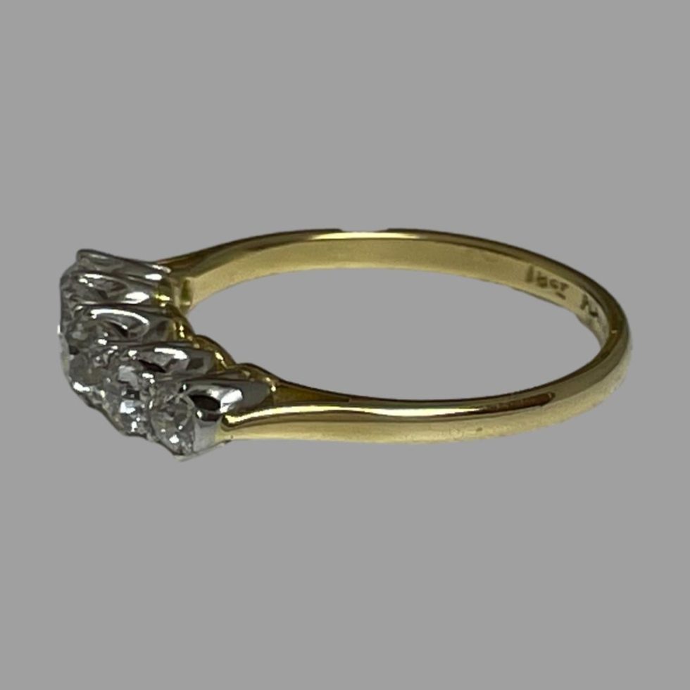 Photo of 18kt gold diamond ring displayed on a flat surface with ring front facing left.