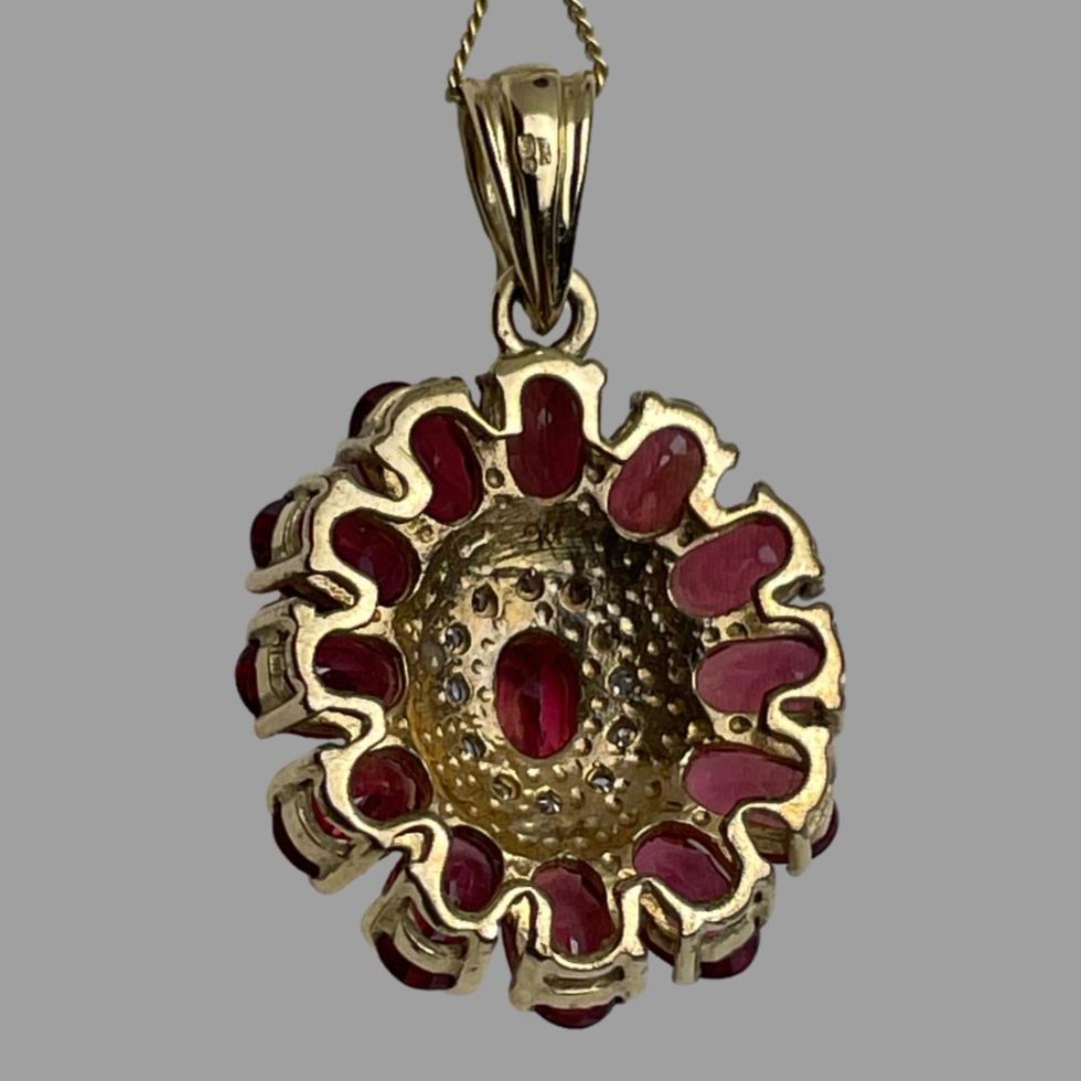 Photo of the back of pendant of gold ruby diamond necklace with the hallmarks to the bail and pendant just visible.