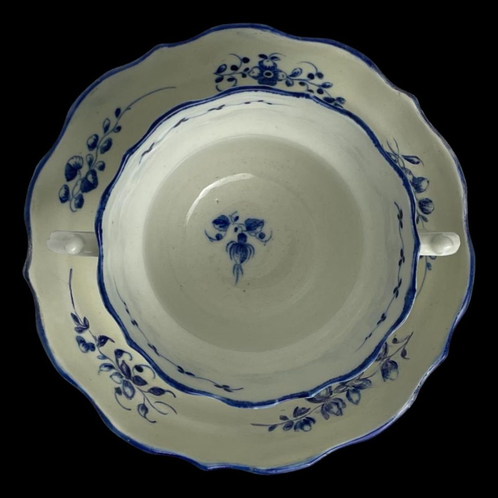 Photo looking straight down at the Caughley chocolate cup & saucer from above. We are looking into the cup which has small blue floral patch on the bottom and the blue floral garlands around the inside rim of the saucer.