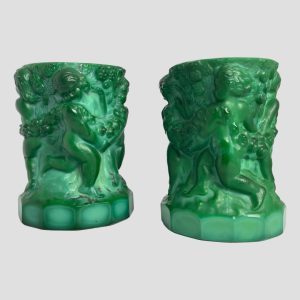 Main photo of malachite glass putti pots seen from an eye level with one side decoration of putti cherubs on show.