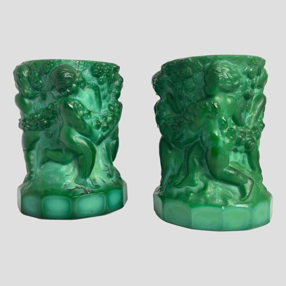 Main photo of malachite glass putti pots seen from an eye level with one side decoration of putti cherubs on show.