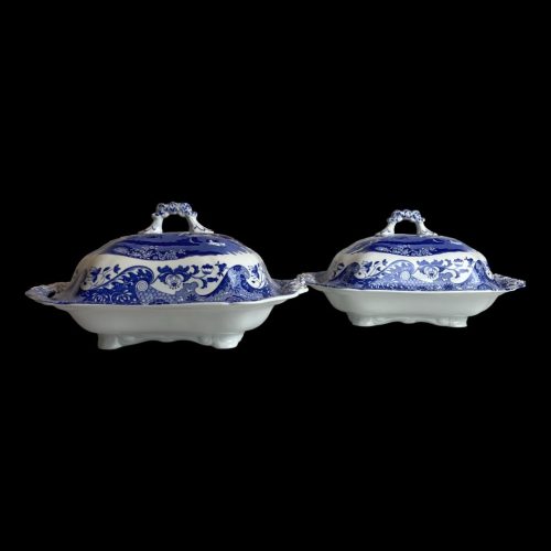 Main photo of pair Spode Italian tureens displayed almost side by side with one slightly in front of other and shown from an eye level. the lower half of tureen exterior is a plain white while the lid shows the Italian design theme. From this angle it is possible to see that the lid has more depth than the bottom part so good for piling up the vegetables!