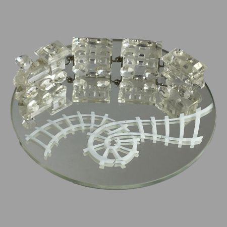 Main photo of Swarovski crystal train set displayed with the train on top of the round mirror with the track (which is painted) in the foreground. The track is very Willy Wonka with a twirl in the centre . The engine of the train is at the left with the carriages attached in a row behind it.