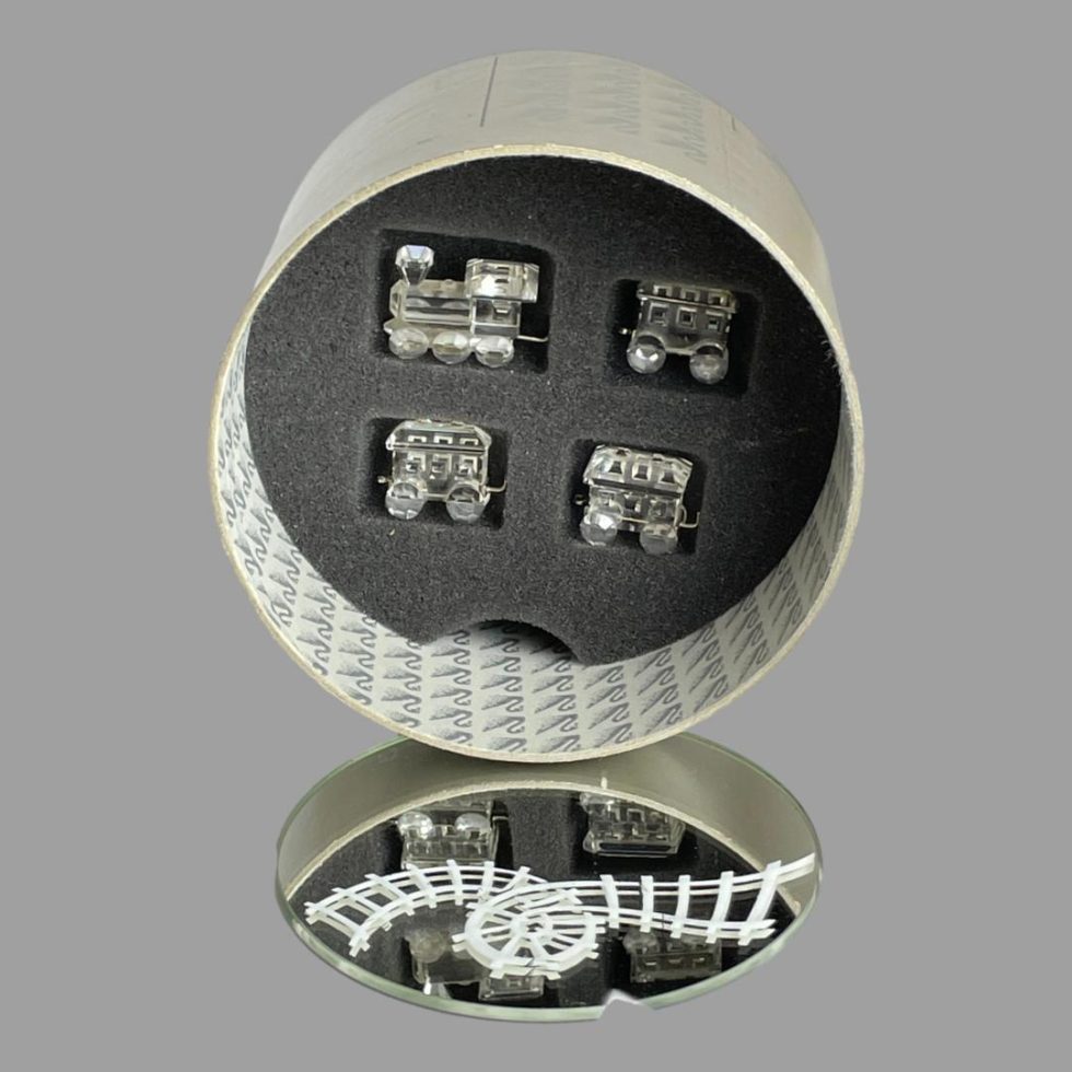 Photo of Swarovski crystal train set displayed with the box open and on its side showing the 4 train pieces neatly packed away inside their fitted foam slots. The mirror track is in the foreground.