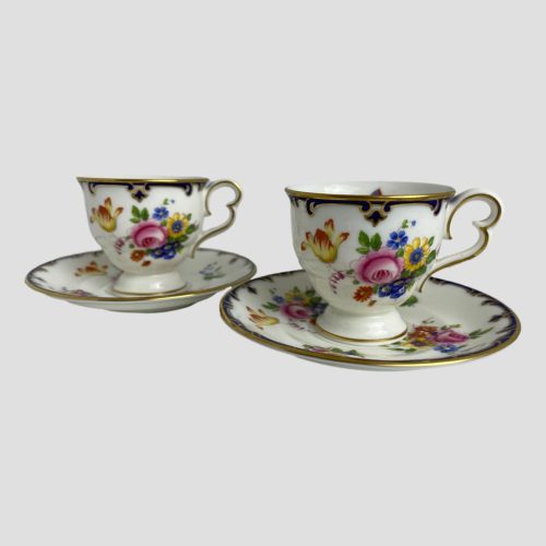 Main photo of both Cauldon cups and saucers displayed side by side with one on right slightly more forward than other. The handles, both to the right, are shaped like the side view of butterfly wings which, given the butterfly theme makes a lot of sense! Beautiful hand-painted flowers adorn the front of the cups.