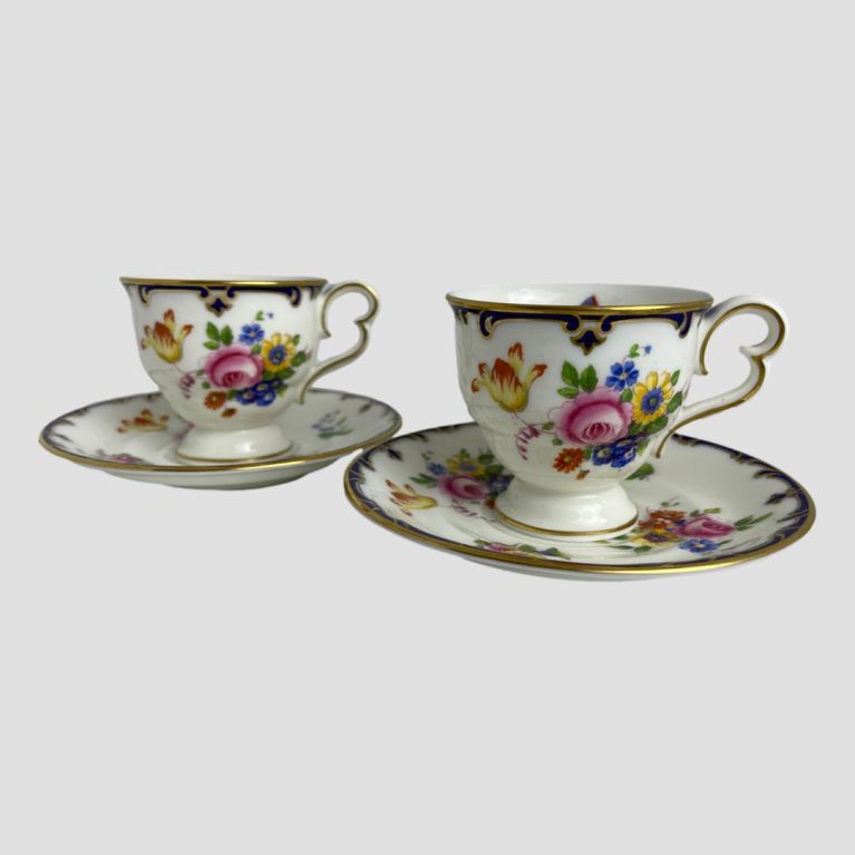 Main photo of both Cauldon cups and saucers displayed side by side with one on right slightly more forward than other. The handles, both to the right, are shaped like the side view of butterfly wings which, given the butterfly theme makes a lot of sense! Beautiful hand-painted flowers adorn the front of the cups.