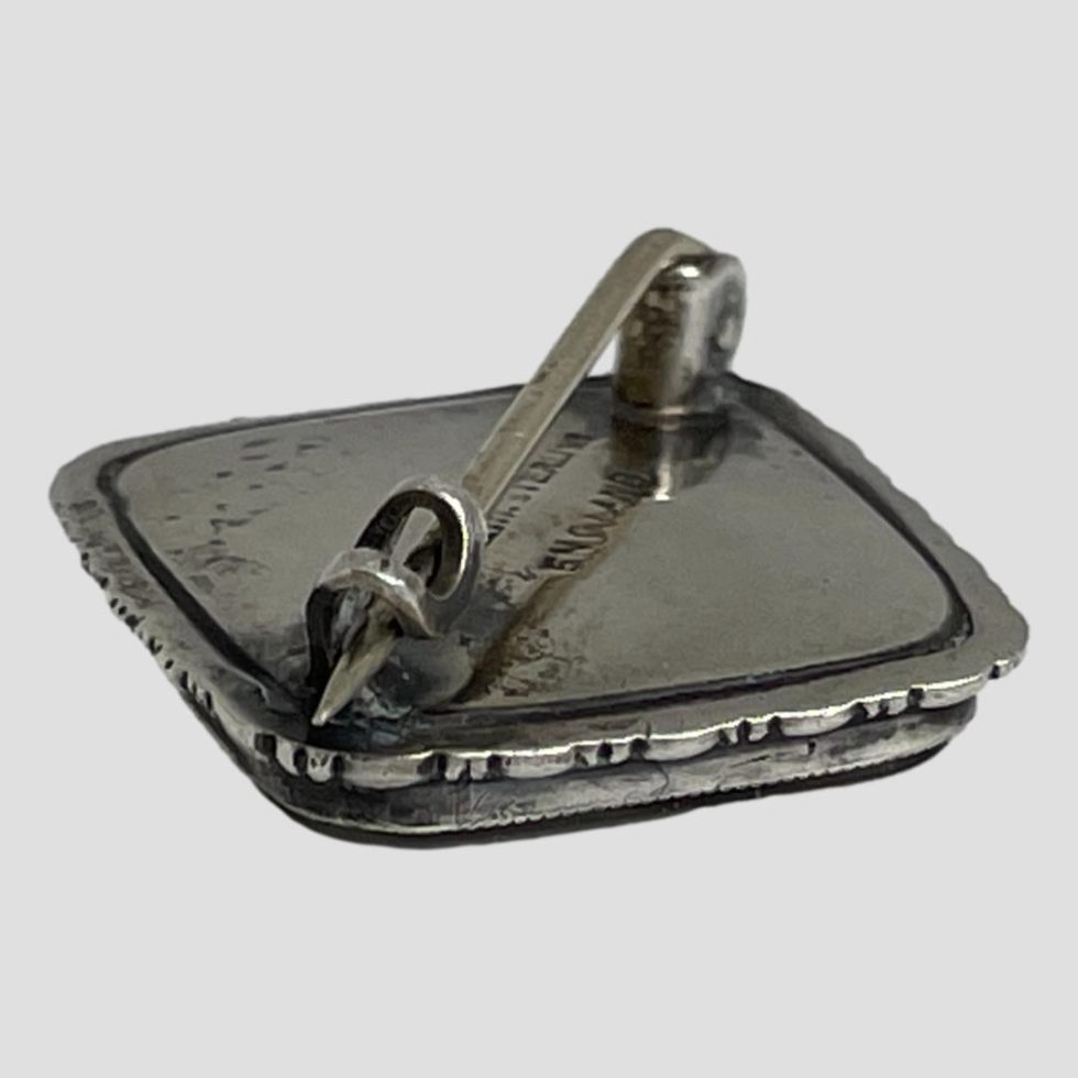 Photo of back of silver butterfly wing brooch with the clasp end in the foreground and shown with pin closed.