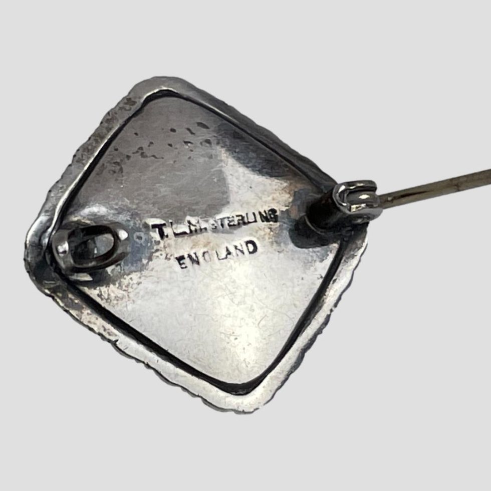 Photo of the back of silver butterfly wing brooch showing the TLM mark and hallmark.