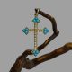 Main photo of antique 18 karat gold cross displayed hanging from a twig of natural cherry wood. The cross is forward facing. The 4 tips of the cross has 3 pointed tips housing 3 small beautiful turquoise blue Sleeping Beauty stones. One stone to pointed tip and 2 immediately behind. 18 seed pearls adorn the rest of the cross. A very pretty piece c1880.