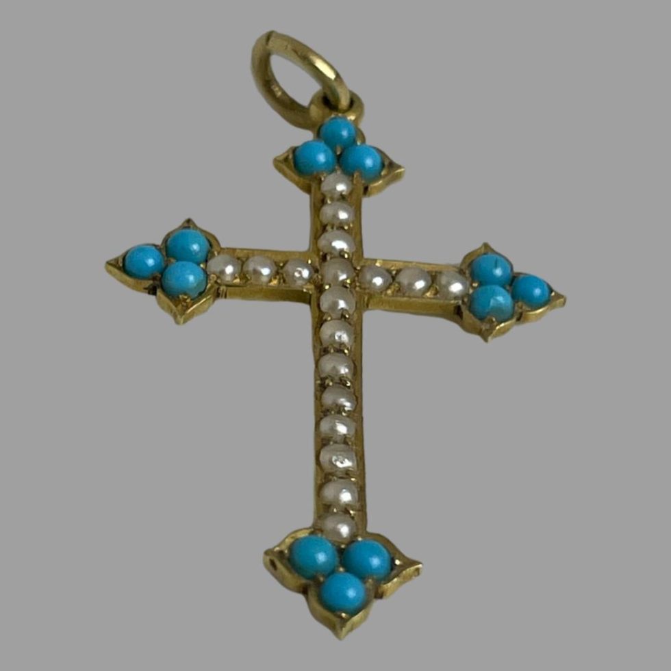 Photo of antique18 karat cross displayed laid flat with the bottom of the cross in the centre foreground.