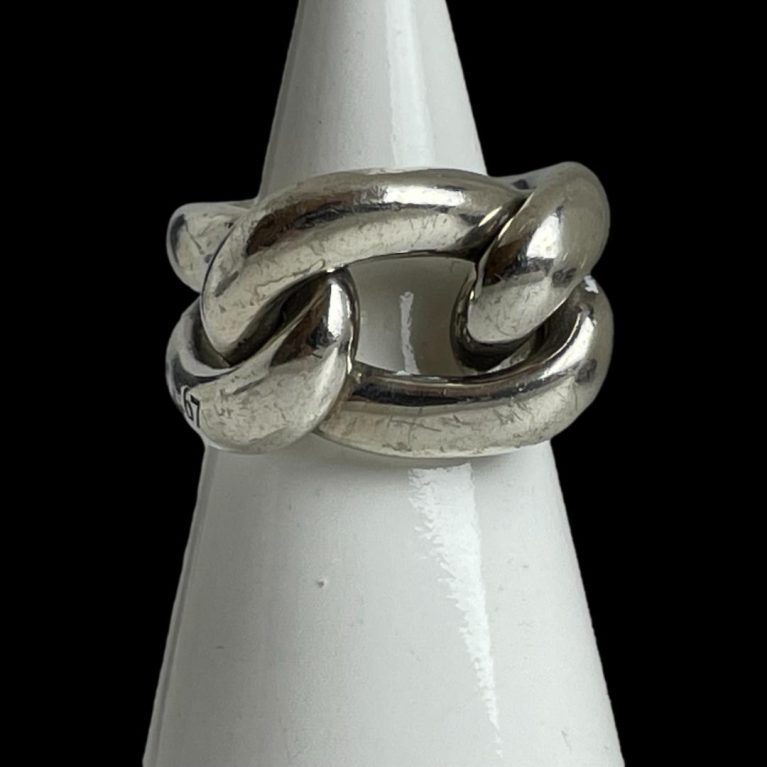 Main photo of Pomellato Gourmet knot ring displayed on a cone shaped white display stand with the ring front forward facing. This ring puts the chunk in chunky! A real statement piece in solid sterling silver. One 'rope' piece makes the shoulders and back bands of the ring while a 'rope circle' is interwoven for the ring front.