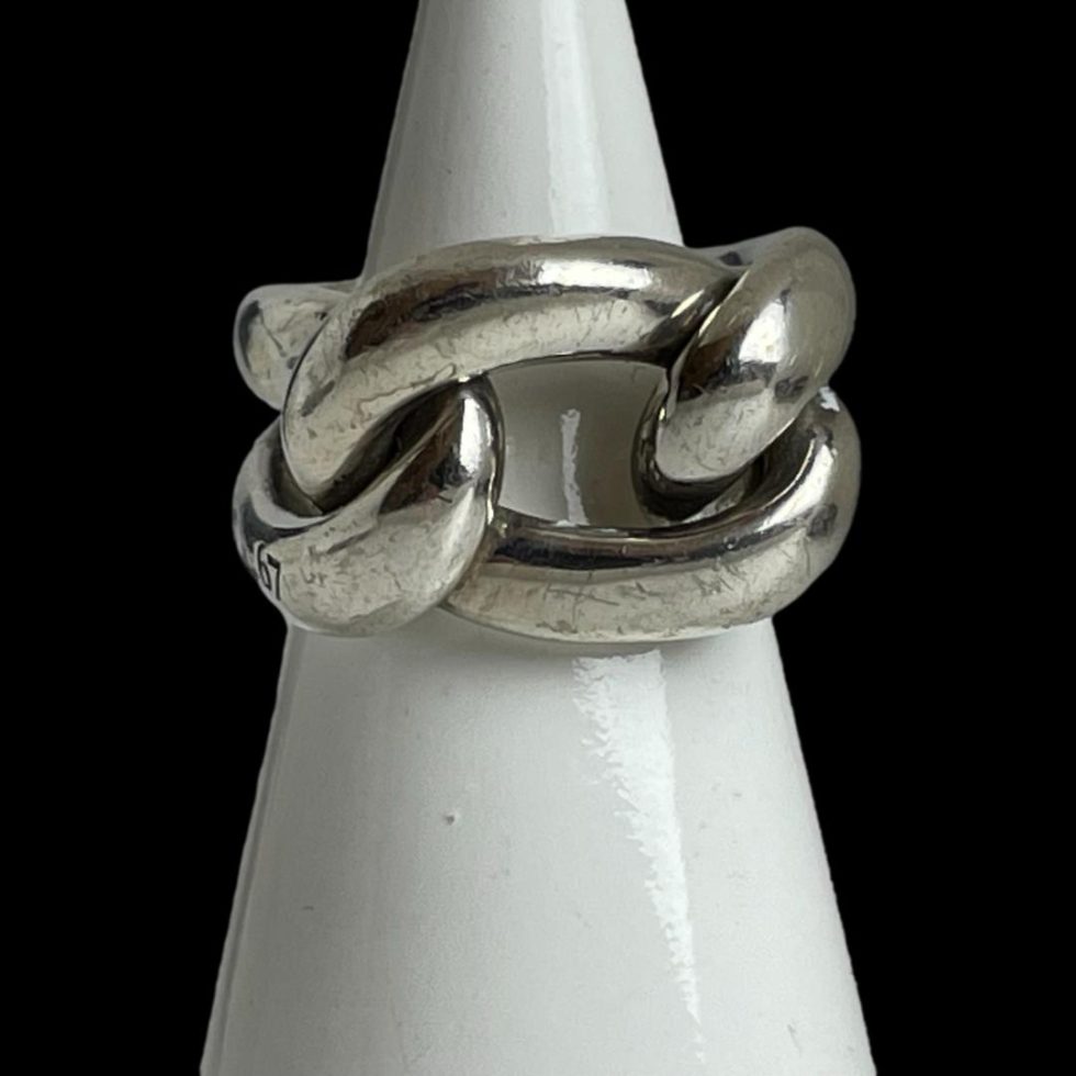 Main photo of Pomellato Gourmet knot ring displayed on a cone shaped white display stand with the ring front forward facing. This ring puts the chunk in chunky! A real statement piece in solid sterling silver. One 'rope' piece makes the shoulders and back bands of the ring while a 'rope circle' is interwoven for the ring front.