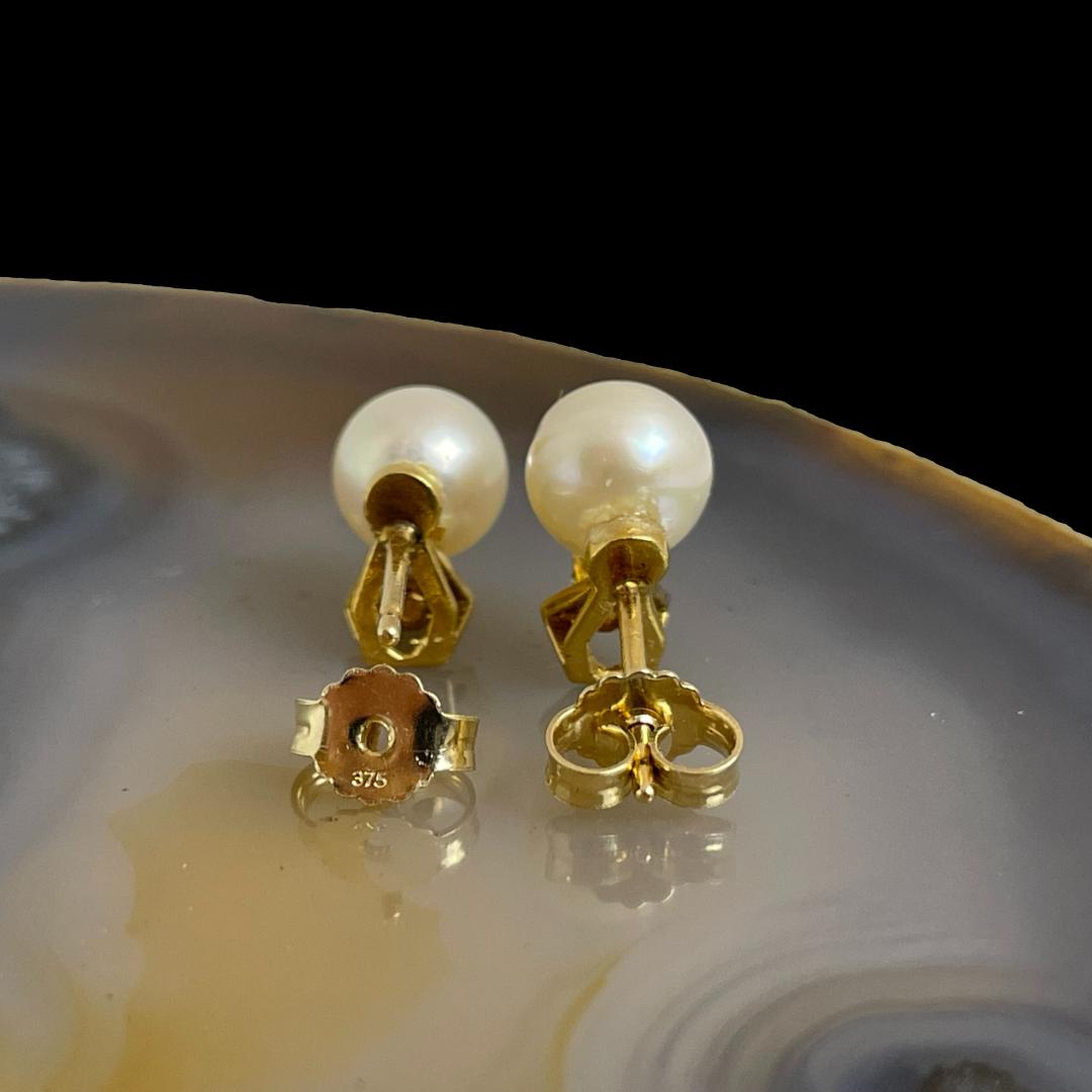 Photo of gold pearl diamond studs displayed on top of a slice of natural agate